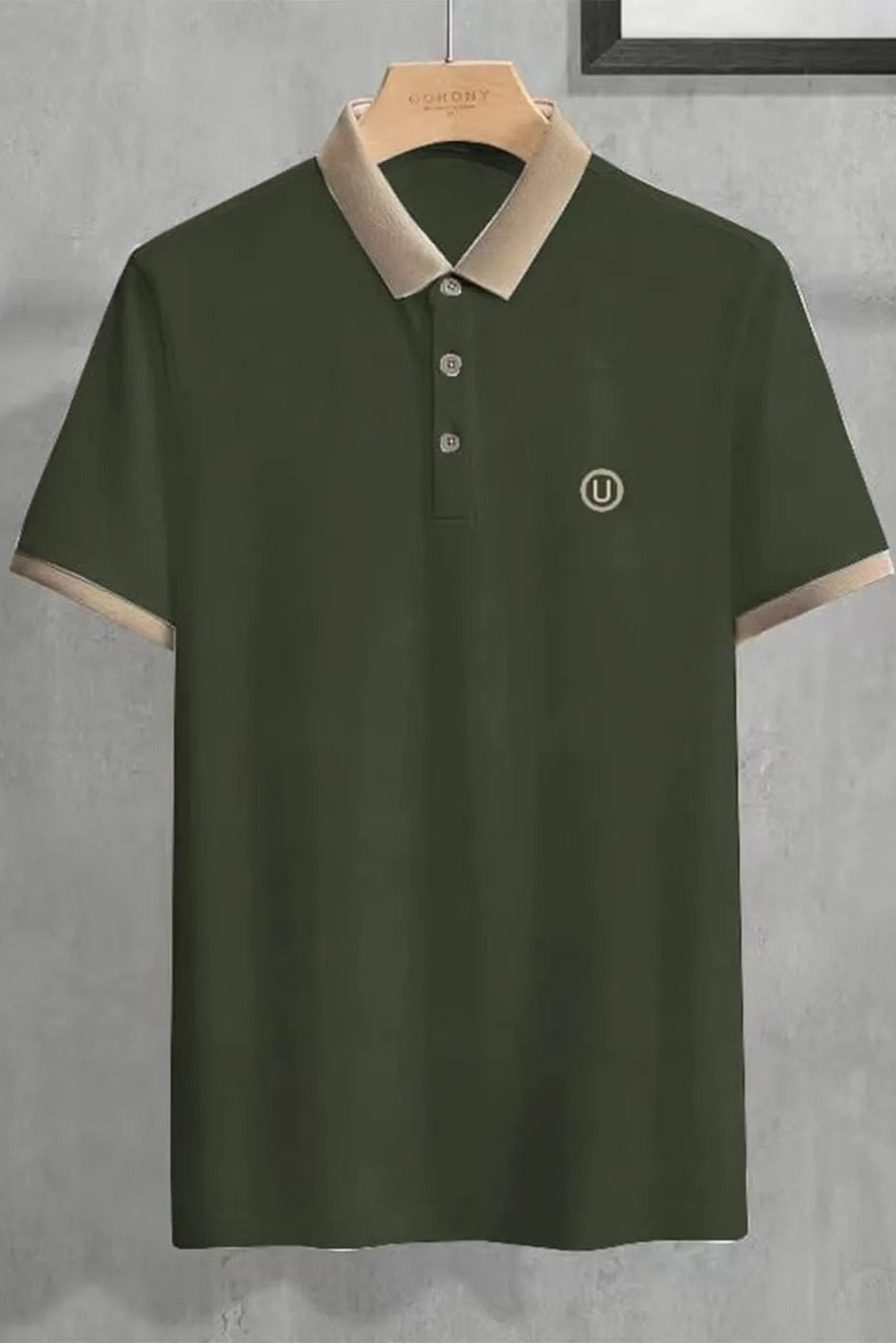Green polo shirt with beige collar on a hanger against a gray background