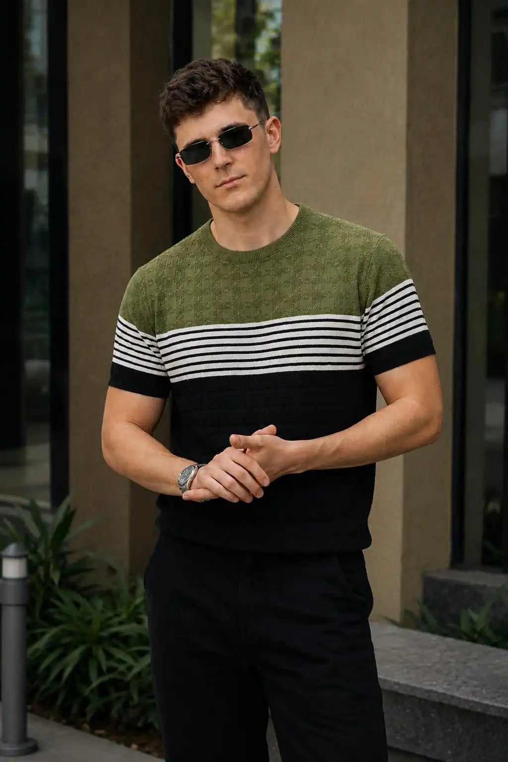 Man wearing a green and black striped sweater with sunglasses and a watch.