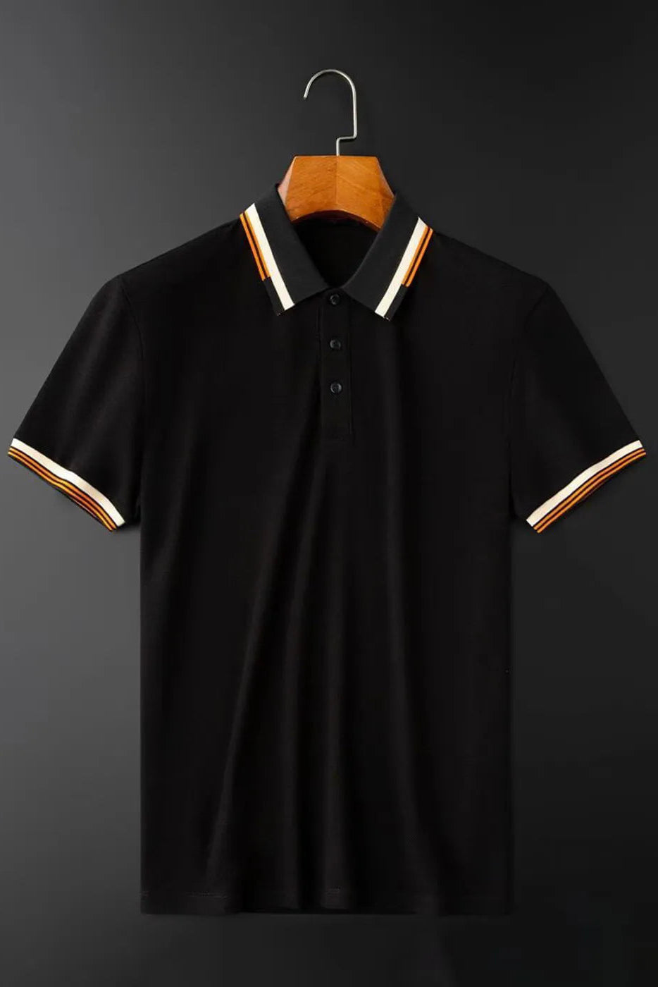 Black polo shirt with striped collar and cuffs on a hanger against a dark background