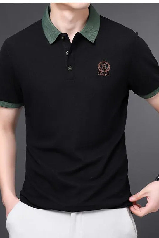 Black polo shirt with green collar and logo on a gray background