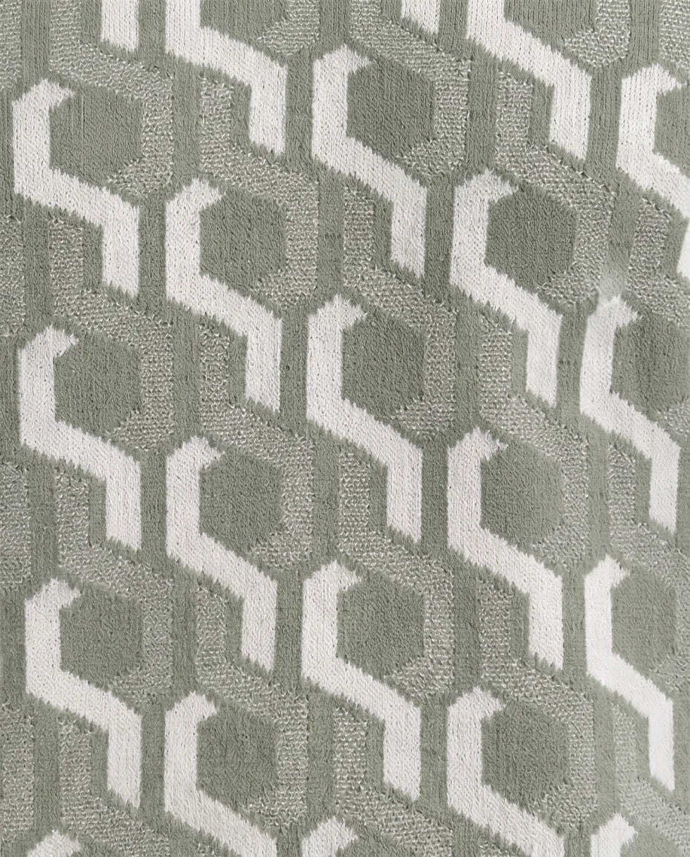 Close-up of the sage green and off-white interlocking geometric jacquard polo knit texture