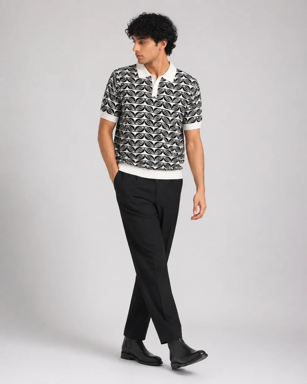 Full-length front view of a model wearing the deep green and white repeating leaf-motif jacquard polo
