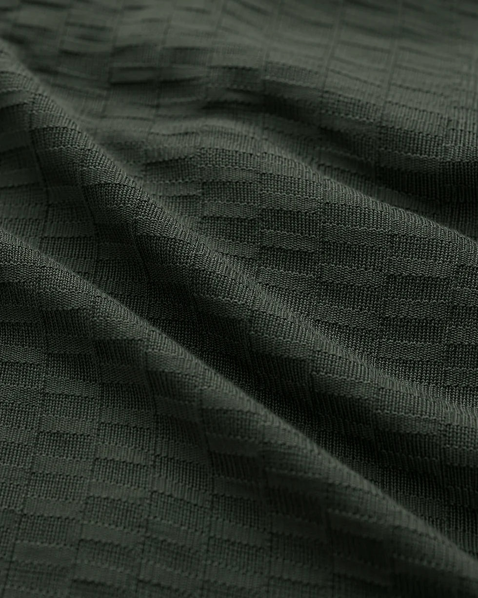 Close-up of the emerald green polo showing its tonal textured knit fabric