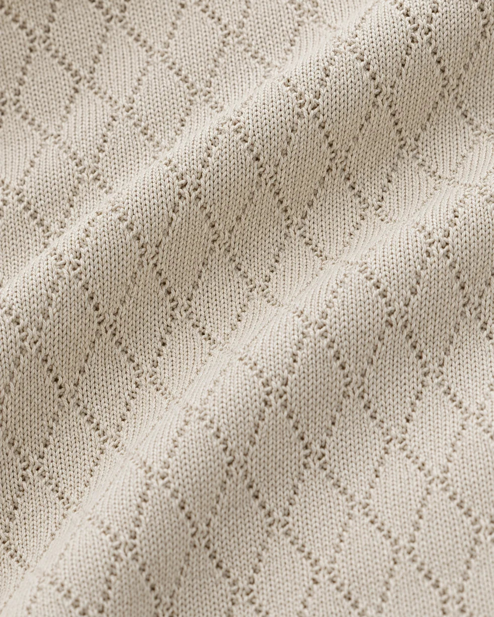 Close-up of the sandstone diamond jacquard polo knit texture