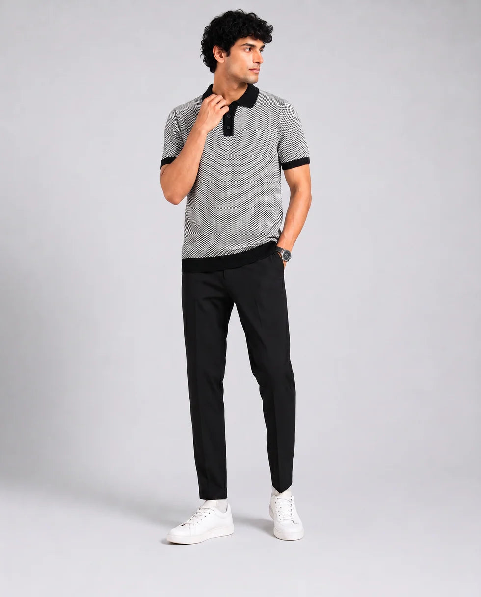 Full-length front view of a model wearing the black and white small-scale monochrome textured knit polo
