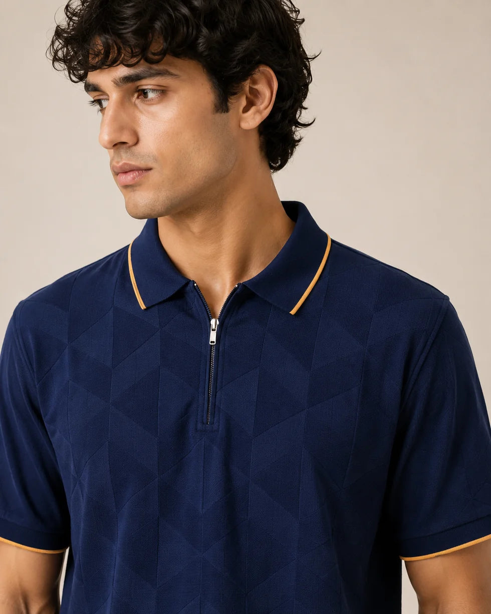 Close front view of the navy blue with orange trim tonal geometric jacquard polo showing its polo collar with zip placket