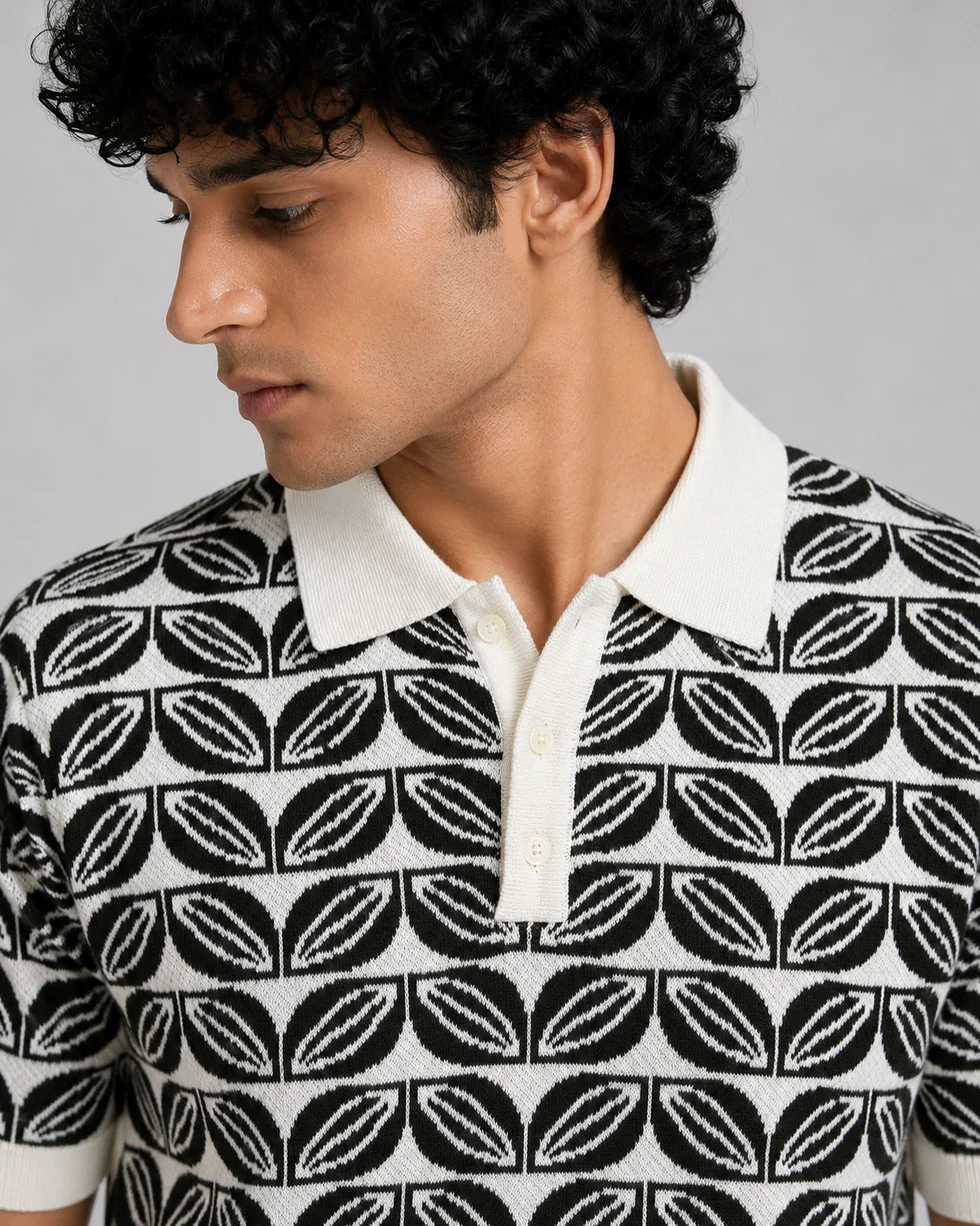 Close front view of the deep green and white repeating leaf-motif jacquard polo showing its polo collar with button placket