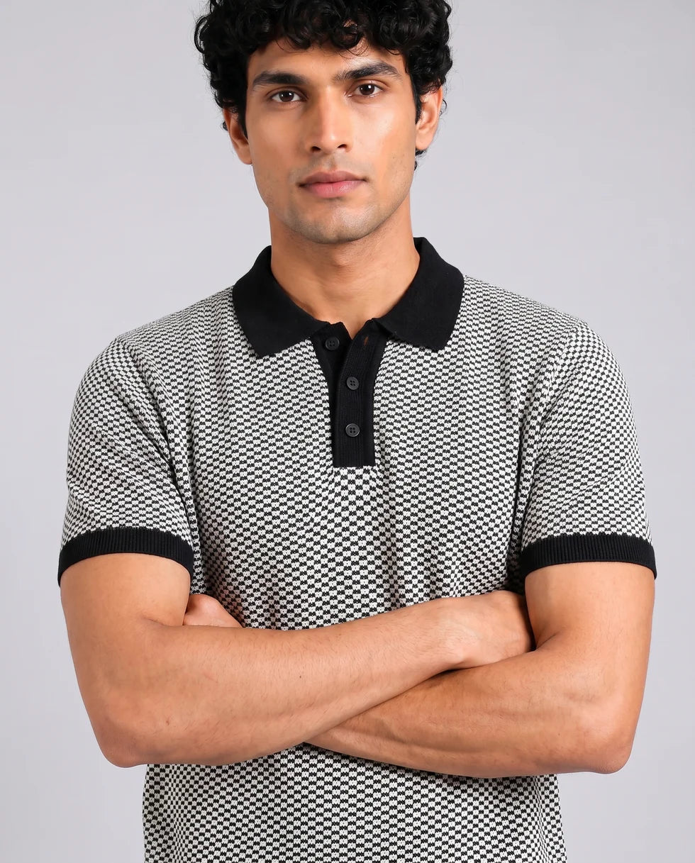 Close front view of the black and white small-scale monochrome textured knit polo showing its polo collar with button placket