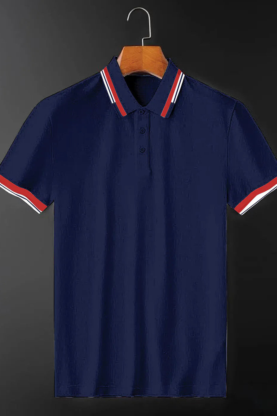 Navy blue polo shirt with red and white striped collar and sleeves on a hanger against a dark background
