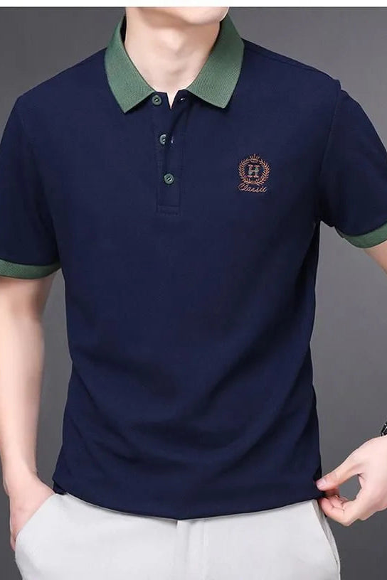 Navy blue polo shirt with green collar and trim worn by a person on a gray background